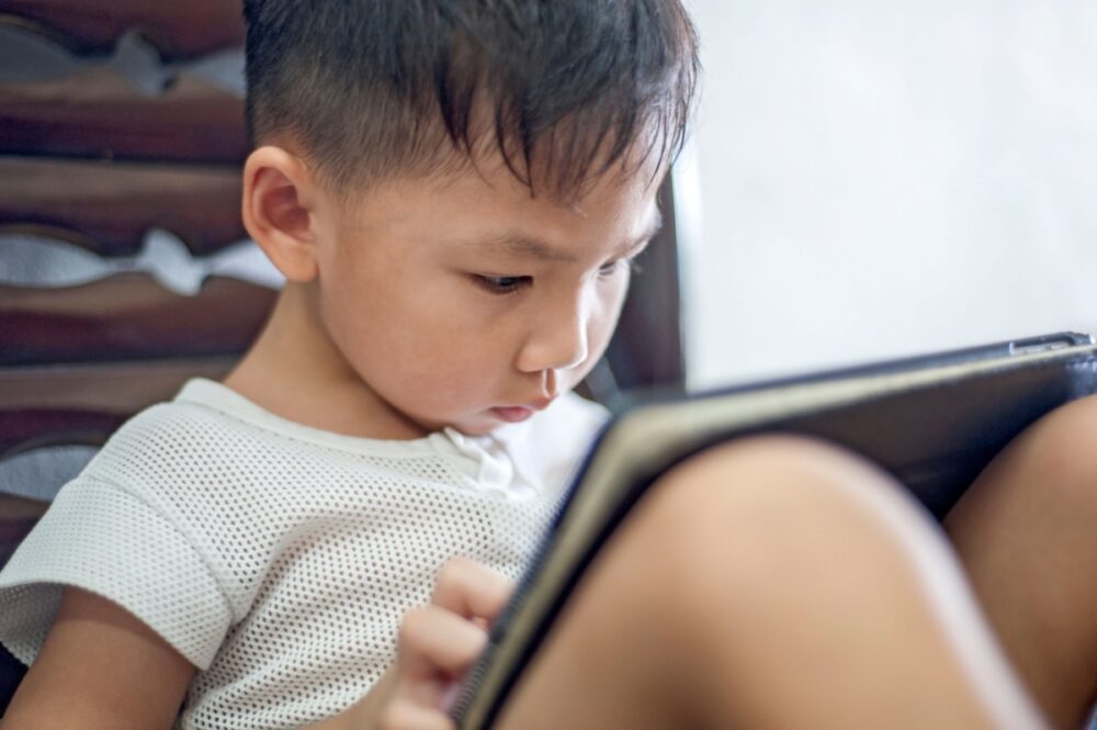 Young boy using a tablet, enjoying a comfortable indoor environment