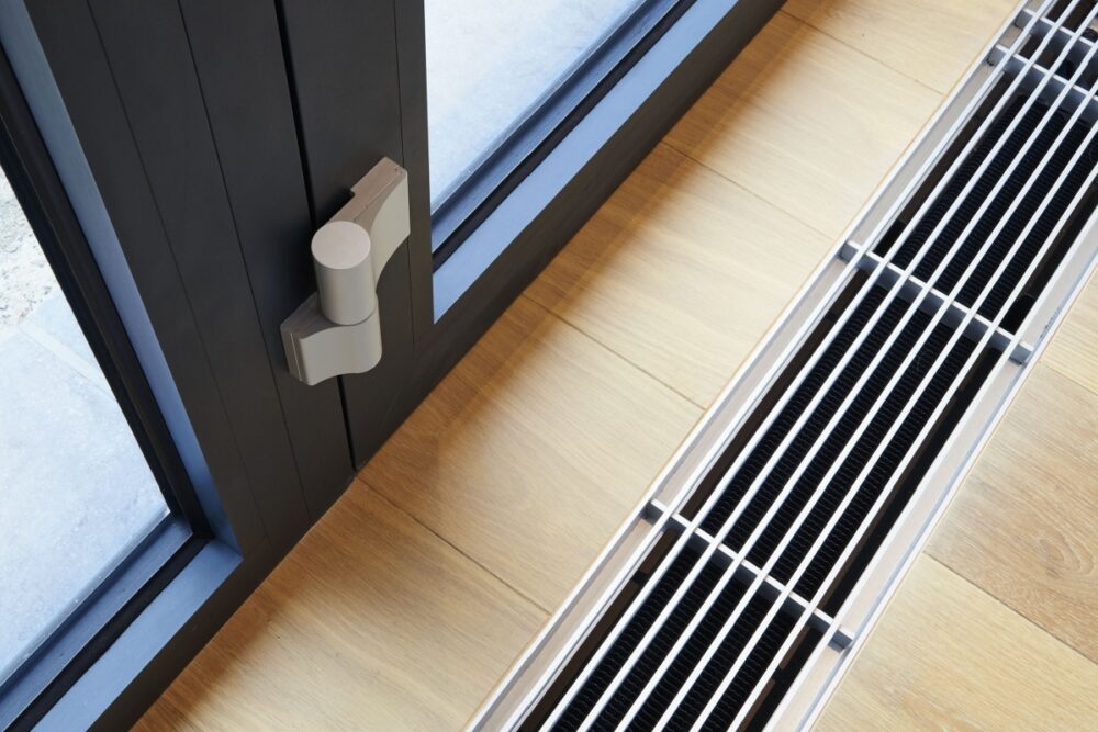 Floor vent with modern design next to a window