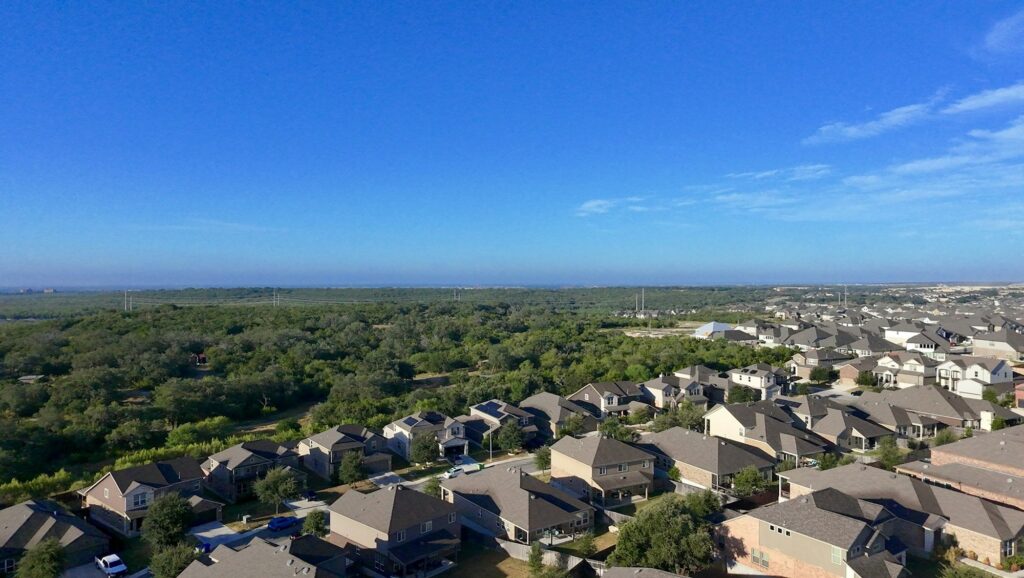 Aerial view of a Texas suburban neighborhood with rows of homes and green trees