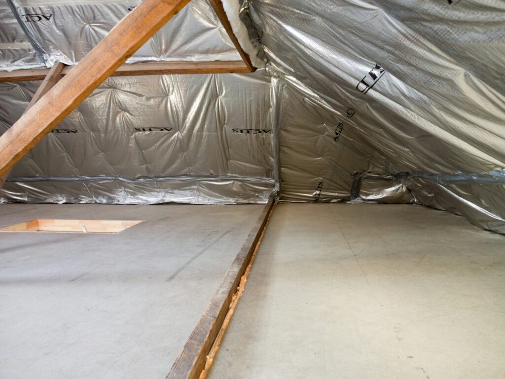 Attic space with foil-faced insulation lining the roof and wood trusses