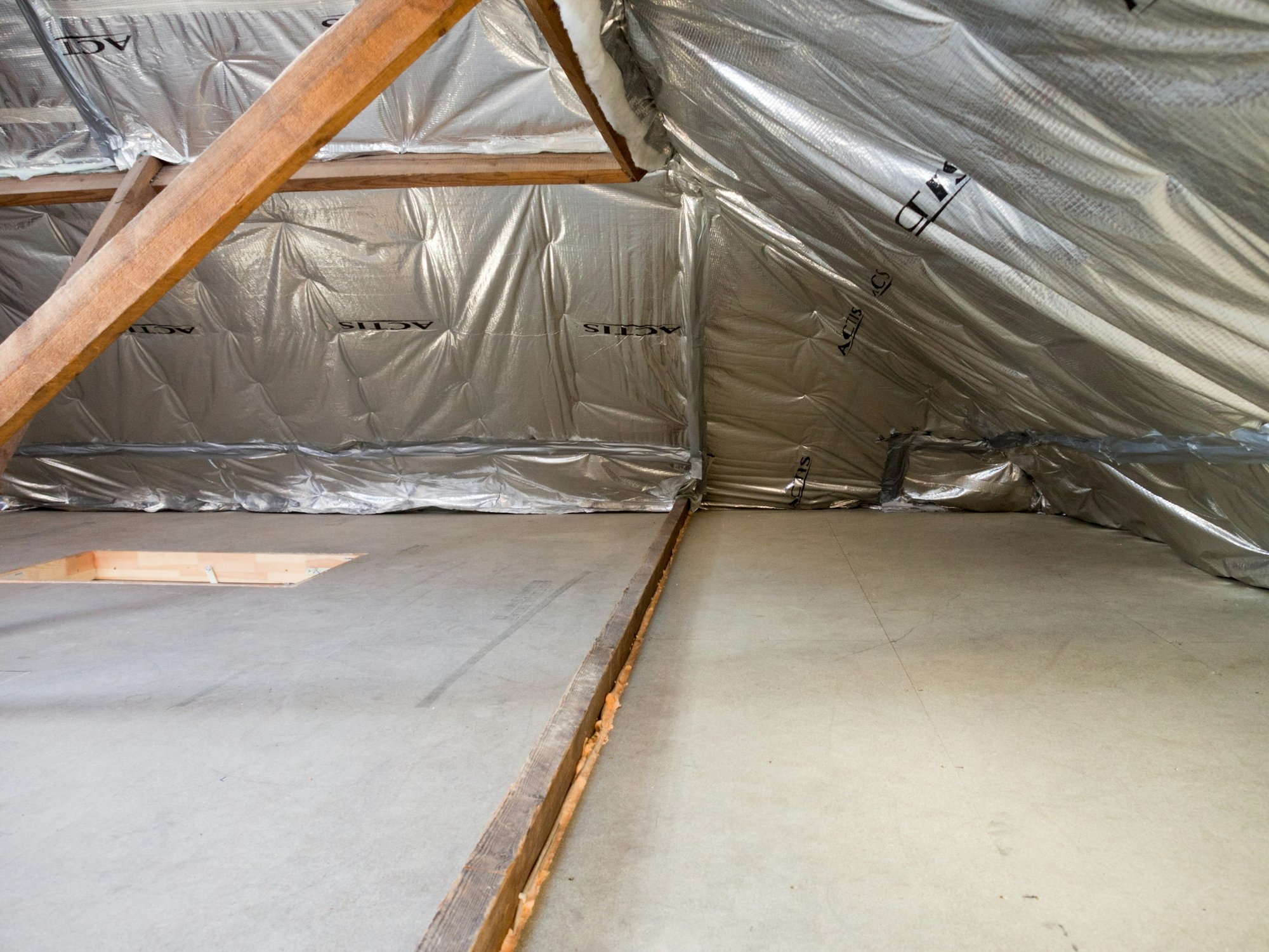 Attic space with foil-faced insulation lining the roof and wood trusses