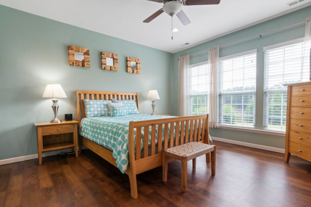 Bright, clean bedroom with a ceiling fan and large windows