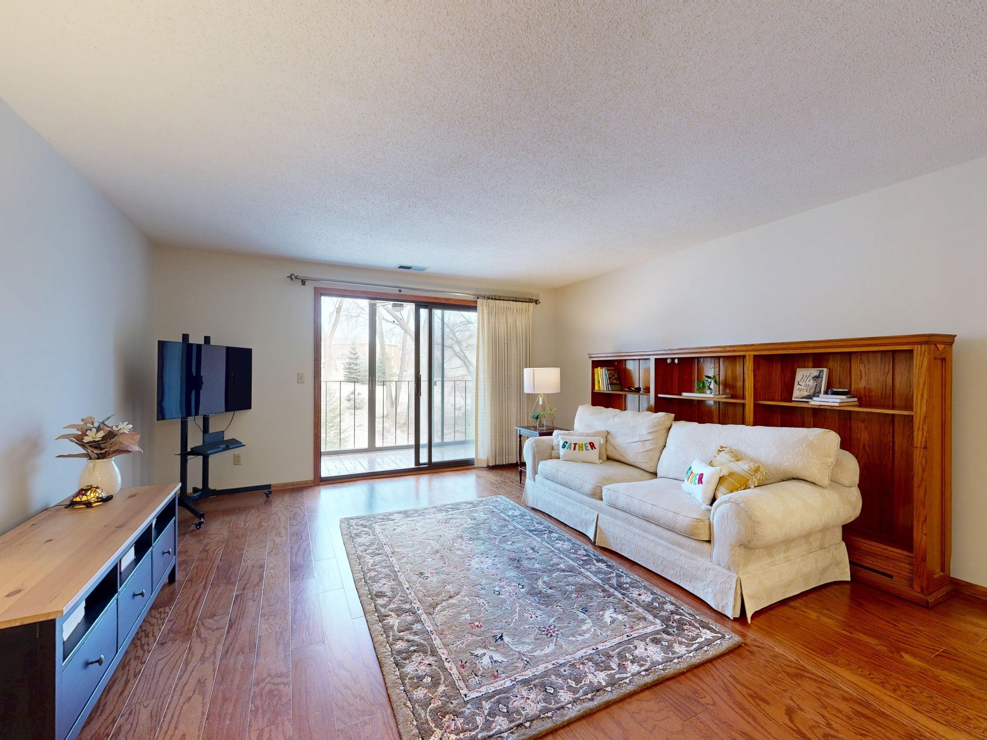 Bright living room with hardwood floors, sofa and sliding patio door