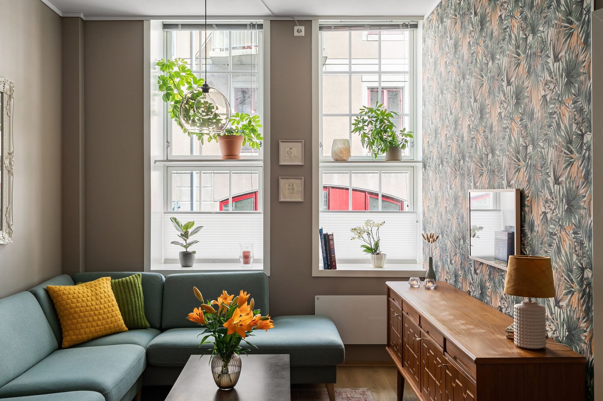Bright living room with large windows, plants and a teal sofa