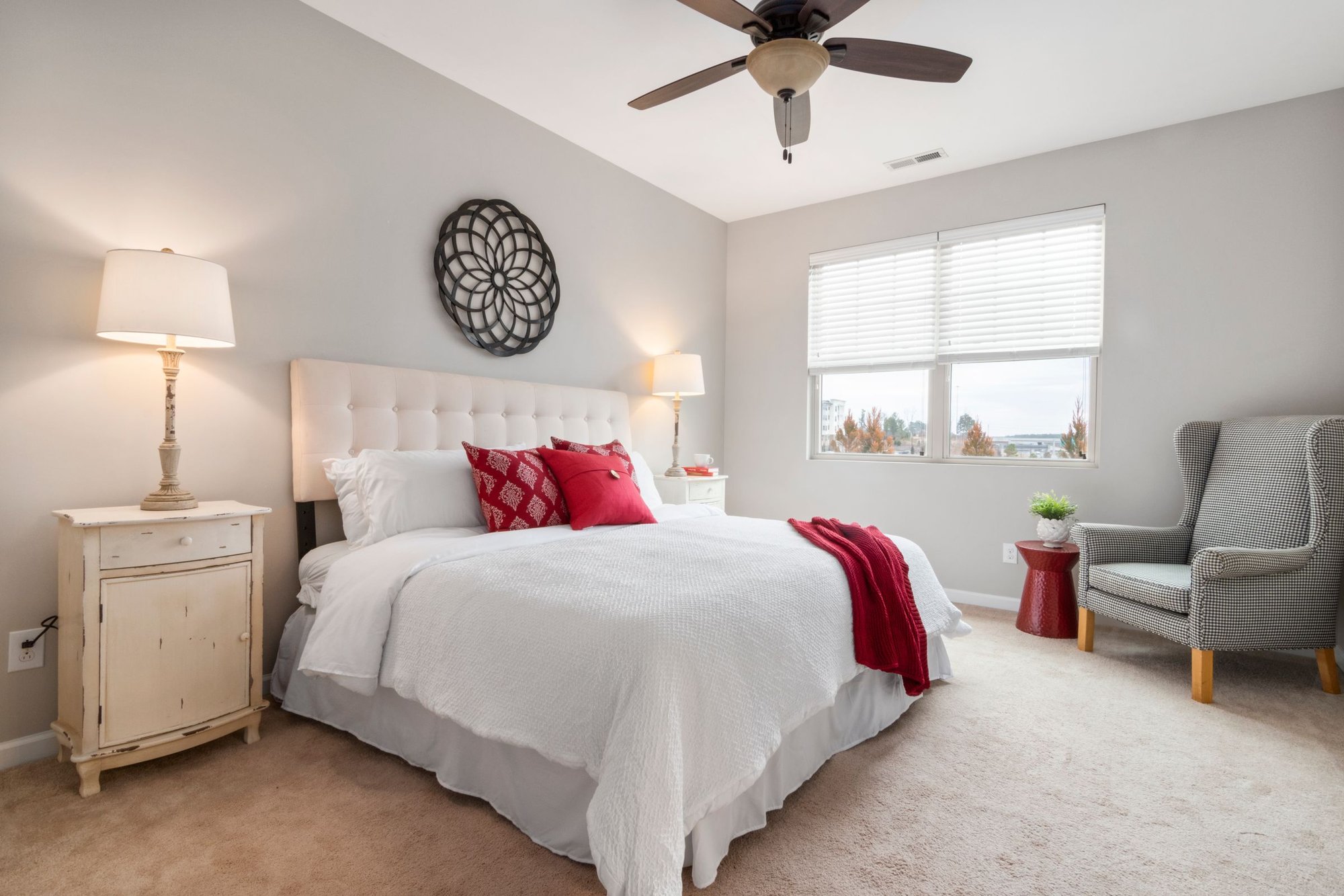 Bright, tidy bedroom with a white bed, ceiling fan and window