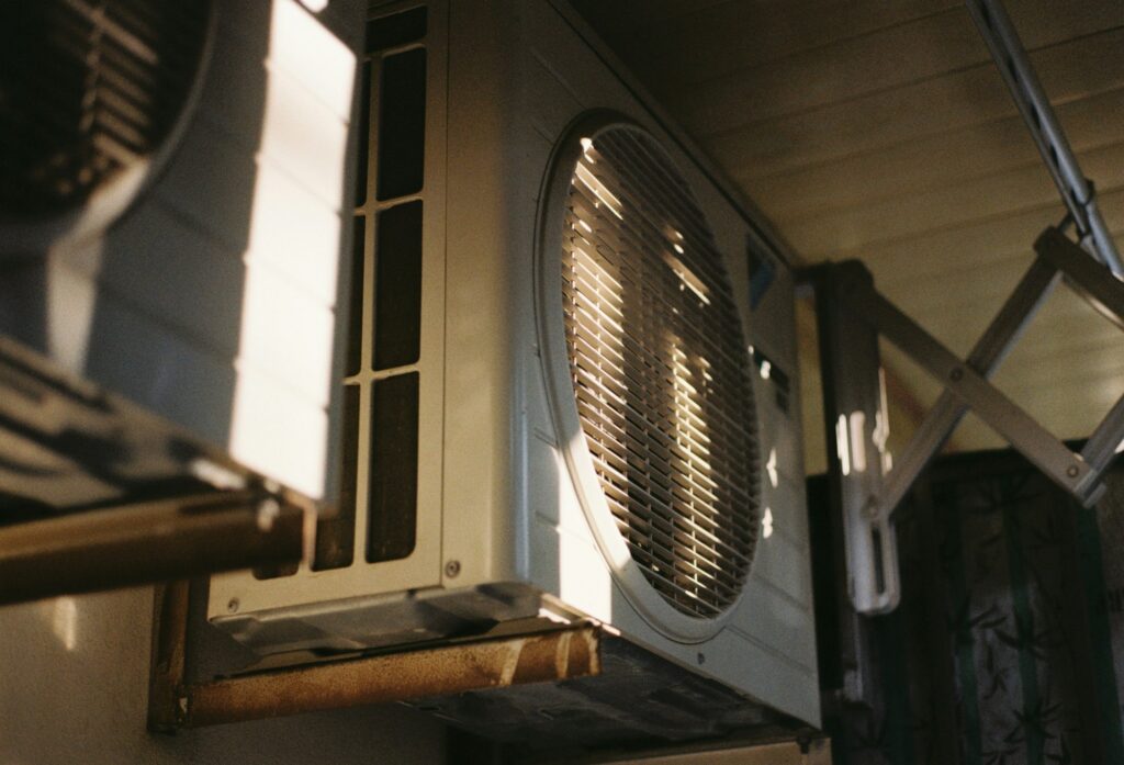 Close-up of an outdoor air conditioner fan grille lit by afternoon sun