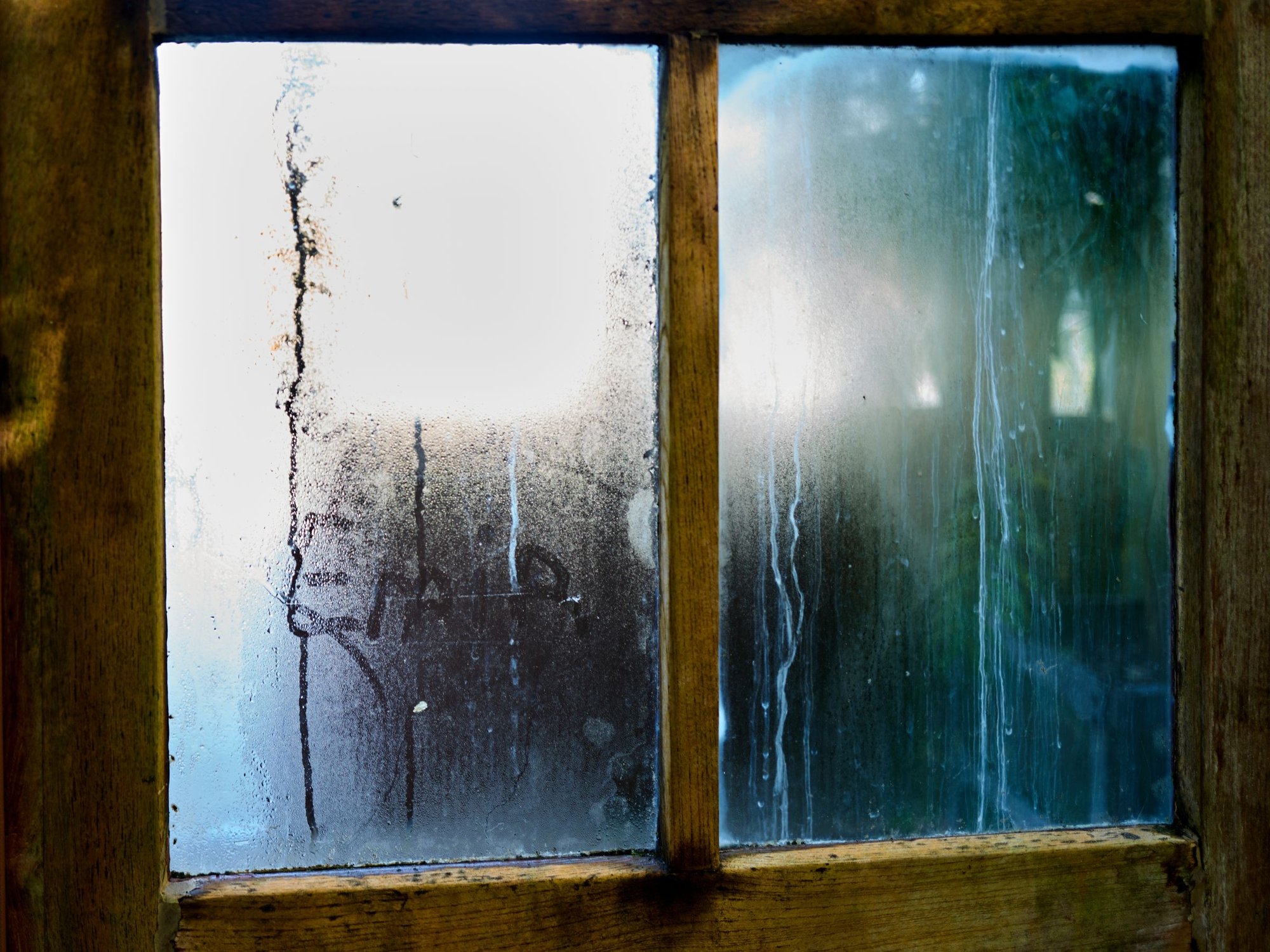 Condensation and water streaks on the inside of a wood-framed window