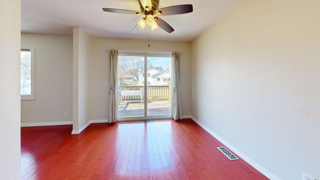 Empty room with a floor air register, ceiling fan and patio doors
