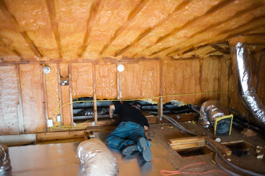 Gold Eagle technician working on flex ductwork in a spray-foam insulated attic