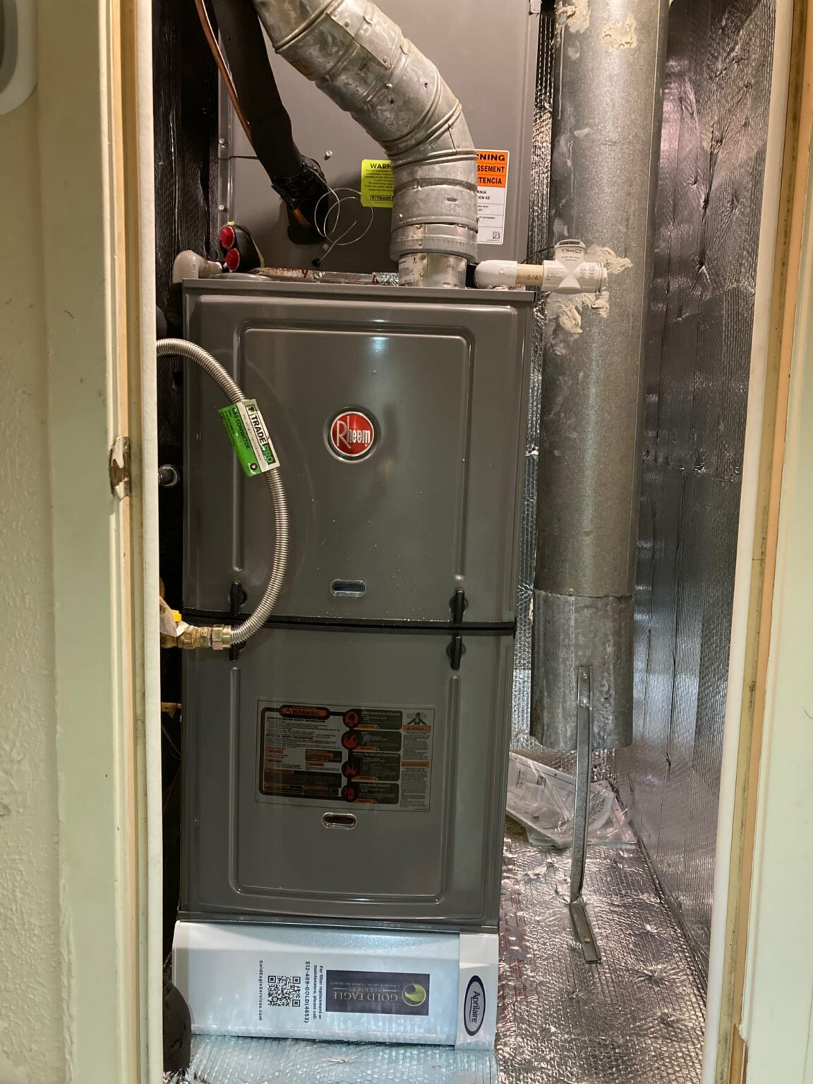 Upflow gas furnace in a closet, with its metal vent pipe rising from the top