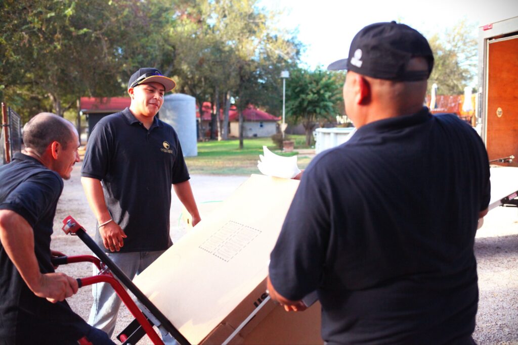 Gold Eagle service manager and installers moving new equipment on a hand truck at a job site