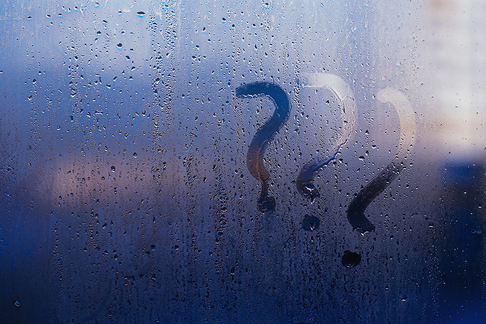 Question marks drawn in condensation on a foggy window