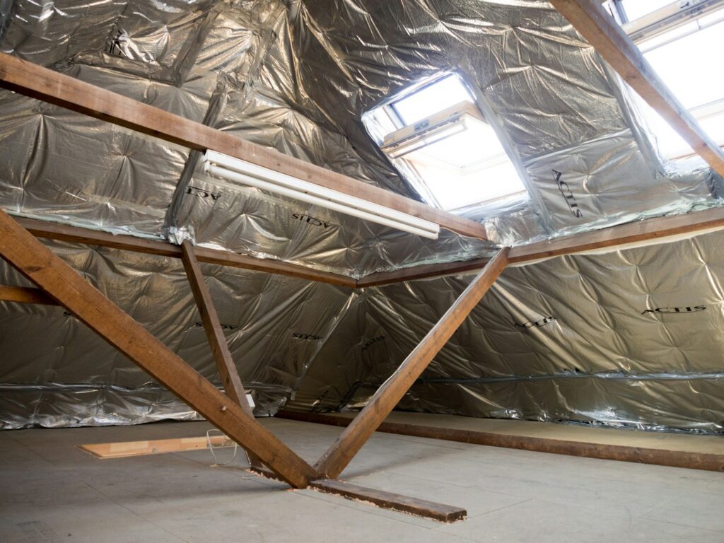 Insulated attic with wood beams and a skylight letting in daylight