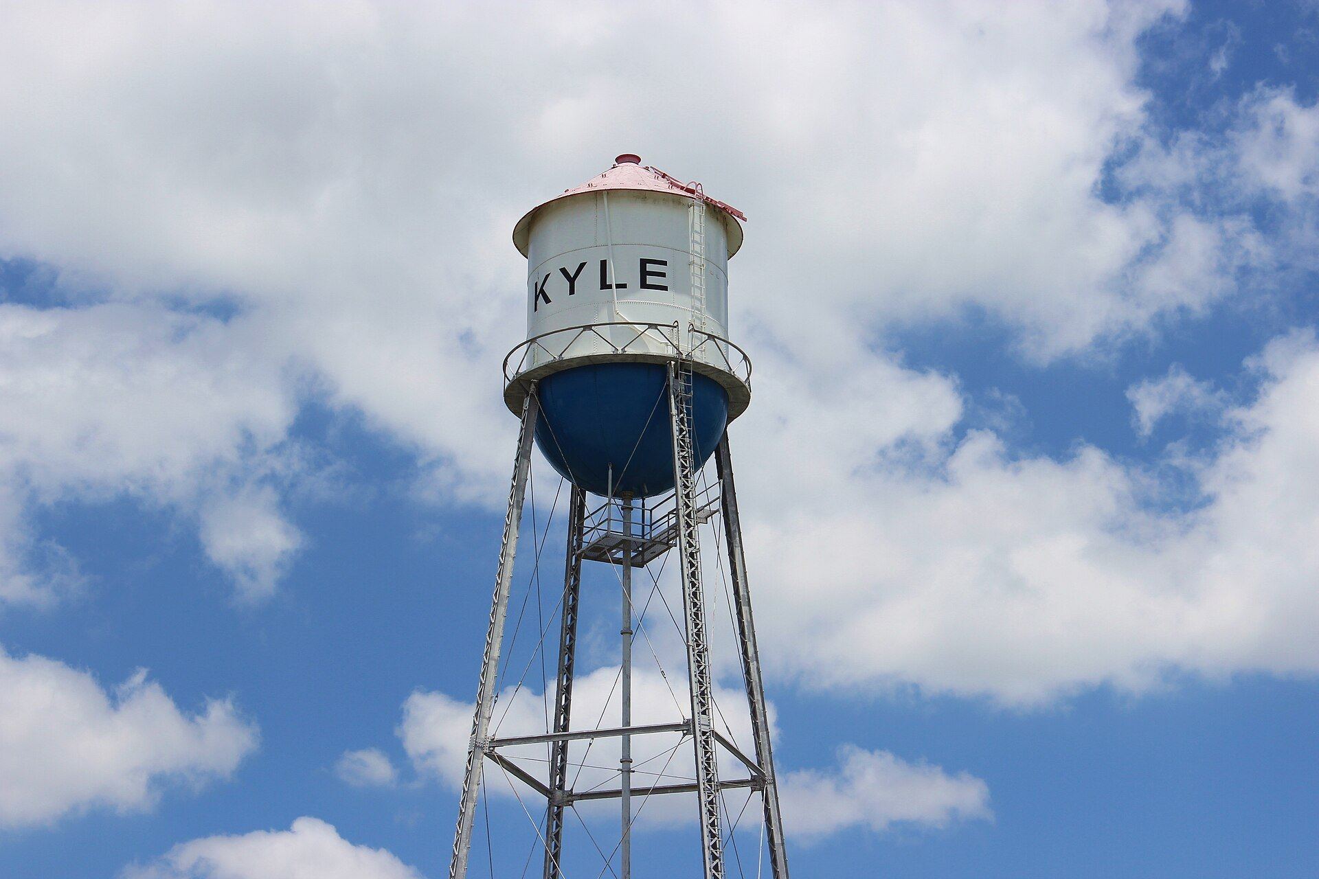 Historic Kyle water tower with KYLE painted on the tank against a cloudy blue sky in Kyle, Texas