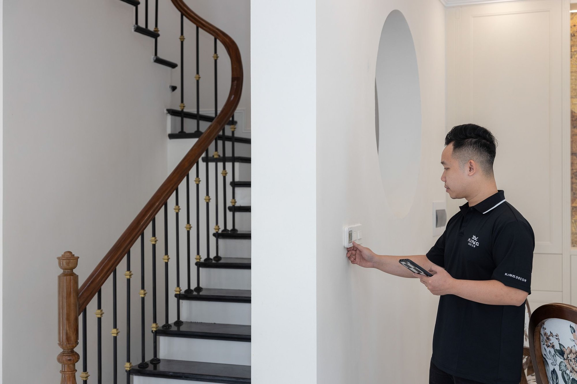 Man adjusting a wall thermostat in a bright home entryway