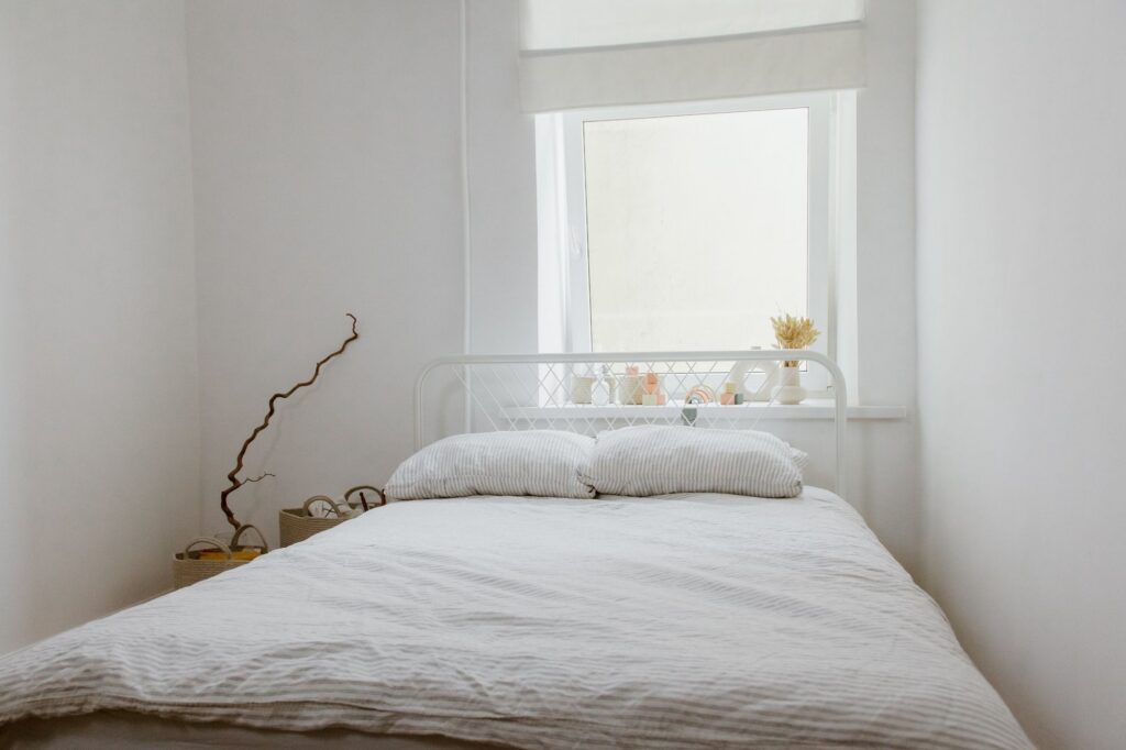 Simple, clean white bedroom lit by natural light from a window