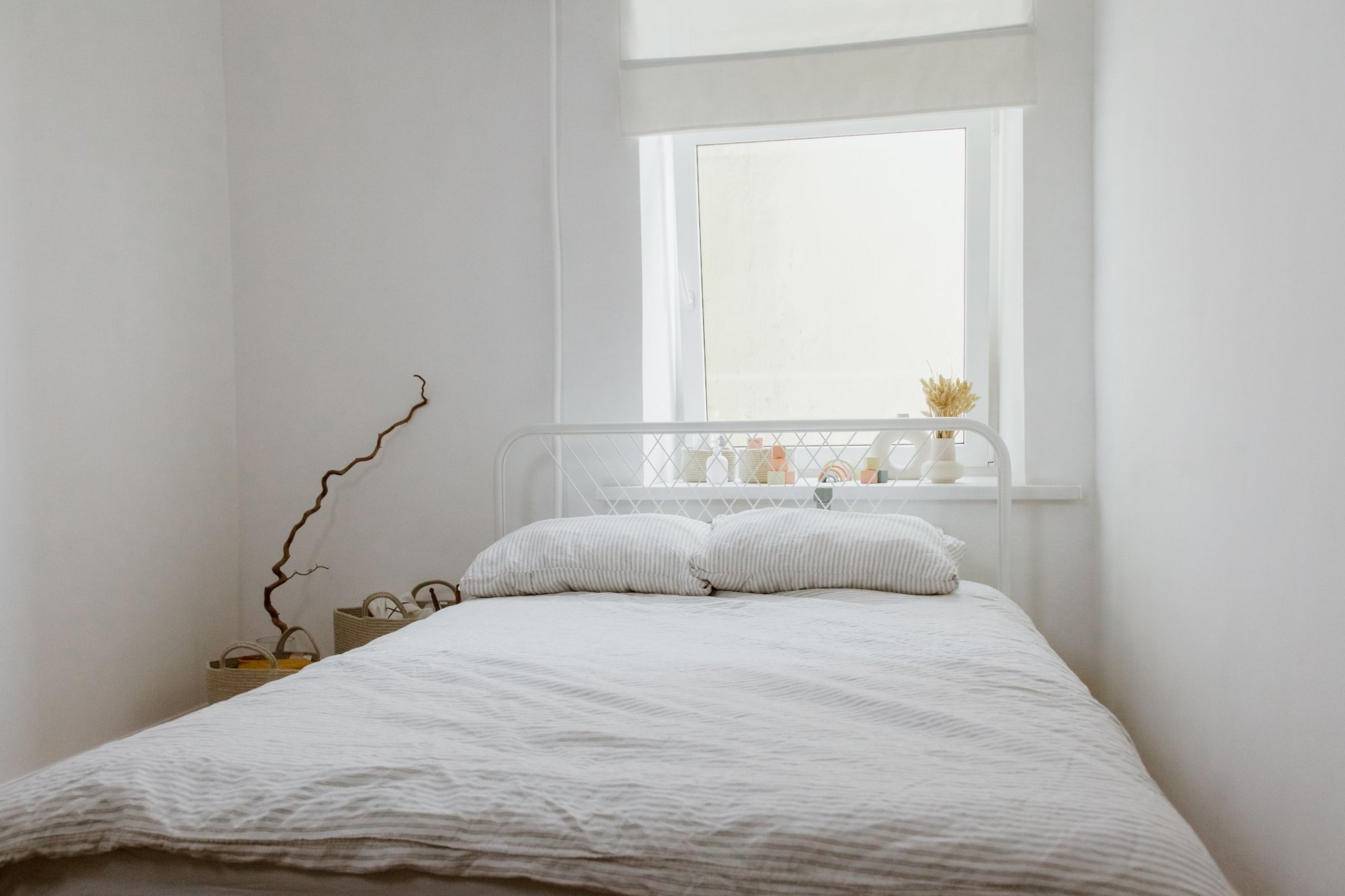 Simple, clean white bedroom lit by natural light from a window