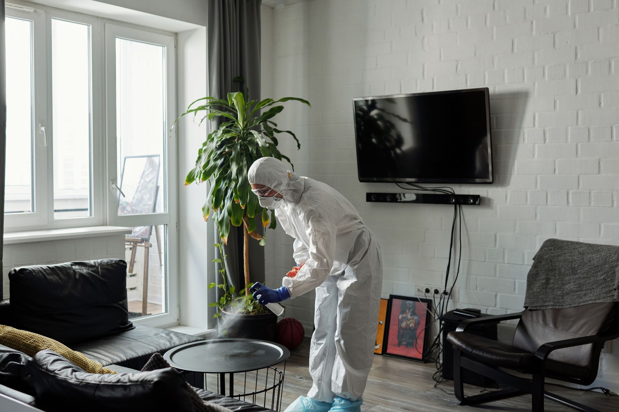 Technician in a protective suit treating a living room