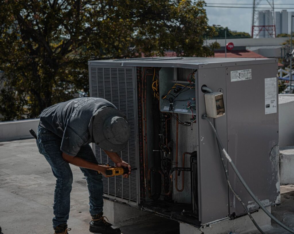 Technician working on an outdoor HVAC unit with its service panel open
