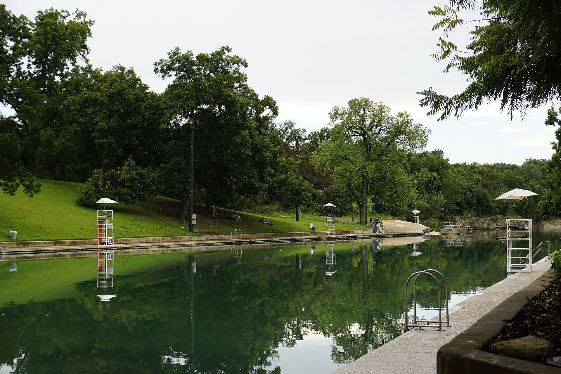 Barton Springs Pool reflecting trees and the grassy hillside in Zilker Park, Austin, Texas